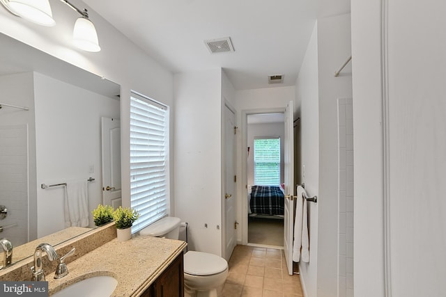 bathroom featuring toilet, vanity, tile patterned flooring, ensuite bathroom, and a shower