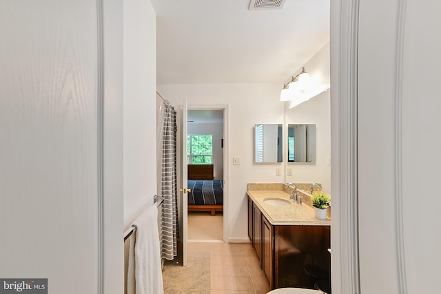 bathroom with vanity, connected bathroom, tile patterned flooring, and baseboards