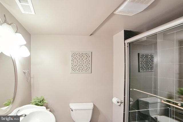 full bathroom featuring a stall shower, toilet, and a sink