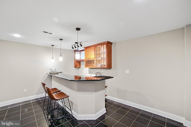 kitchen featuring a breakfast bar, baseboards, brown cabinetry, glass insert cabinets, and recessed lighting