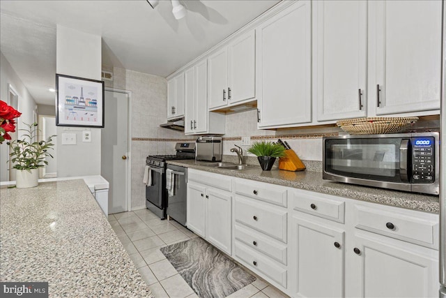 kitchen featuring stainless steel appliances, under cabinet range hood, white cabinets, a sink, and light tile patterned floors