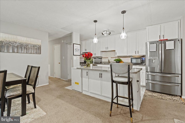 kitchen with stainless steel fridge with ice dispenser, light carpet, white cabinetry, a center island, and decorative light fixtures
