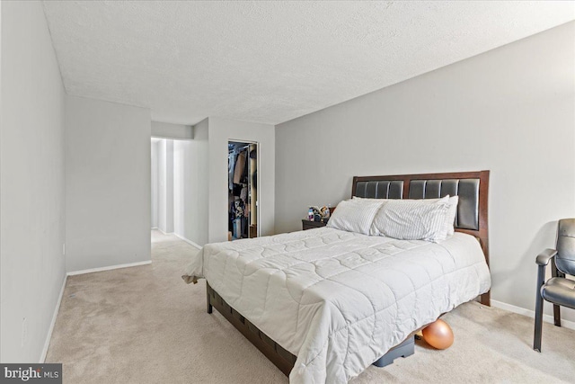 carpeted bedroom with baseboards, a textured ceiling, a walk in closet, and a closet