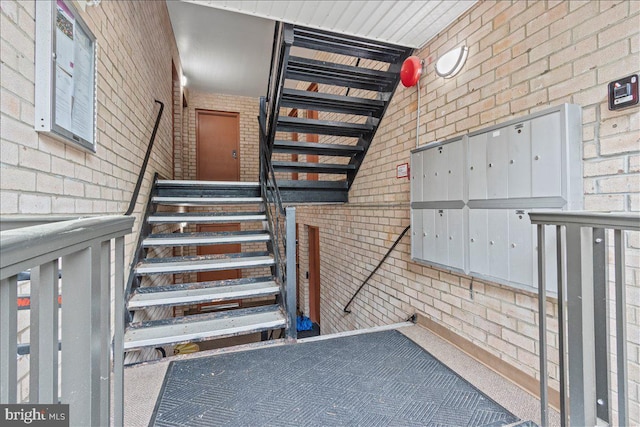 stairway featuring brick wall, mail area, and carpet flooring
