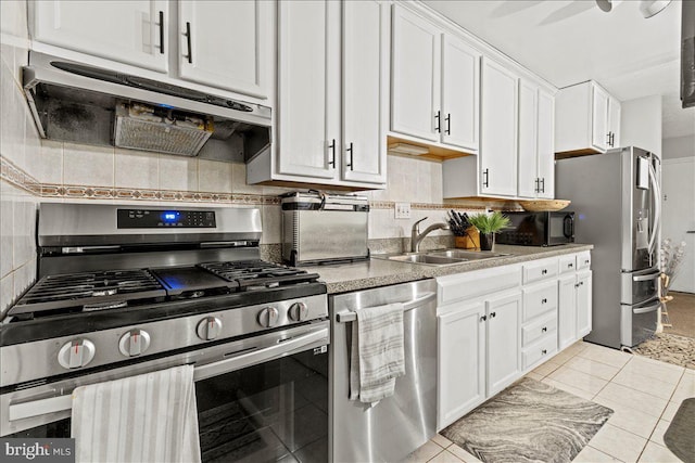 kitchen with stainless steel appliances, under cabinet range hood, a sink, and backsplash