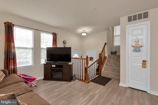 living room featuring wood finished floors, baseboards, and stairs
