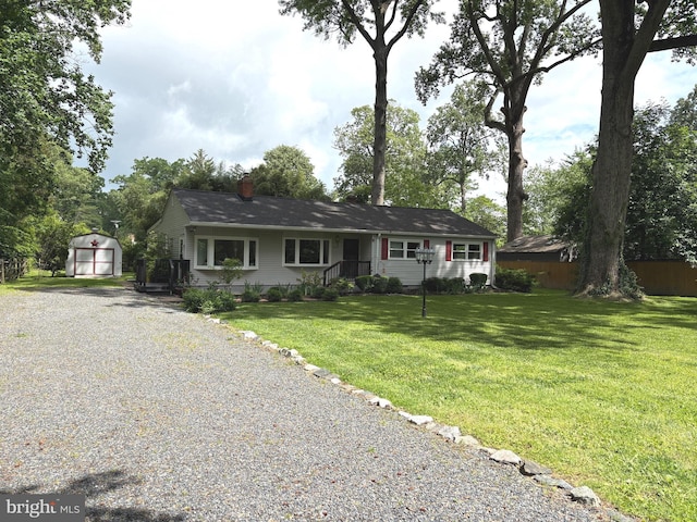 view of front of property with gravel driveway, a storage shed, an outdoor structure, a front yard, and a chimney