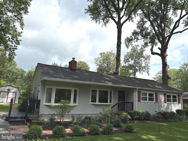 view of front facade featuring an outbuilding, a chimney, a shed, and a garage