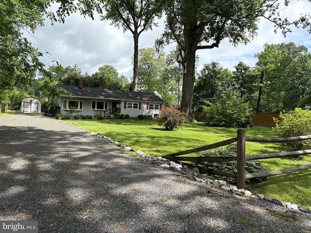 ranch-style home with a storage shed, an outdoor structure, and gravel driveway