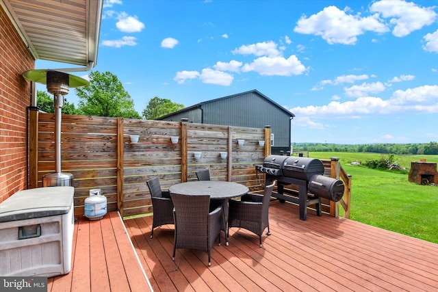 wooden deck with a lawn, outdoor dining space, and area for grilling