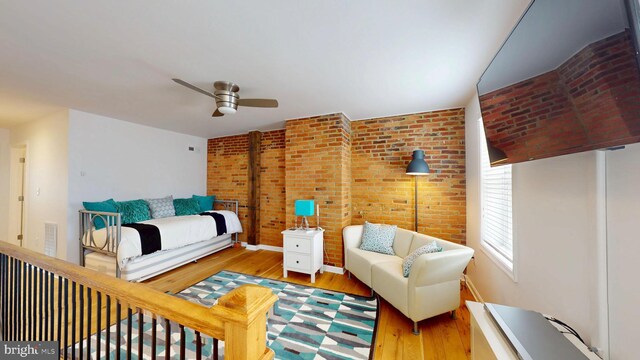 306 S Exeter St, Baltimore, MD 21202 - bedroom with wood finished floors, brick wall, a ceiling fan, and baseboards