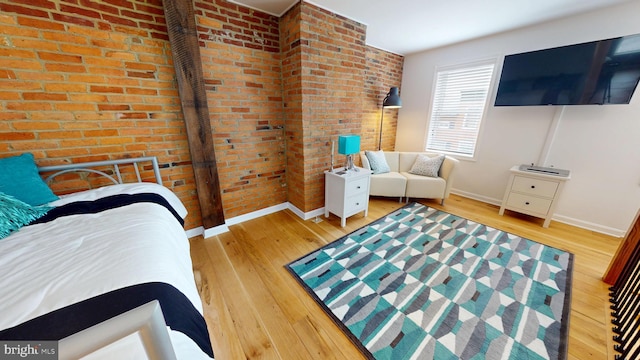306 S Exeter St, Baltimore, MD 21202 - bedroom featuring hardwood / wood-style floors, baseboards, and brick wall