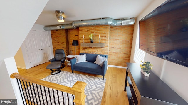 306 S Exeter St, Baltimore, MD 21202 - living area featuring wood finished floors, baseboards, and brick wall