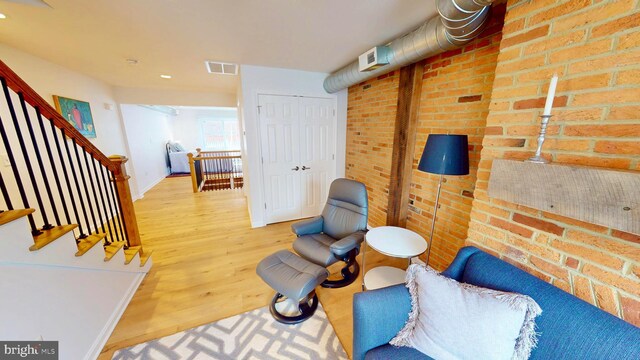 306 S Exeter St, Baltimore, MD 21202 - living area featuring wood finished floors, baseboards, an upstairs landing, recessed lighting, and brick wall