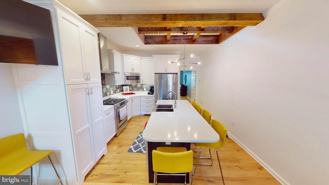 306 S Exeter St, Baltimore, MD 21202 - kitchen featuring appliances with stainless steel finishes, beamed ceiling, a sink, a chandelier, and wall chimney exhaust hood