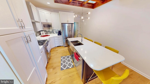 306 S Exeter St, Baltimore, MD 21202 - kitchen with appliances with stainless steel finishes, a center island with sink, white cabinets, a sink, and light countertops