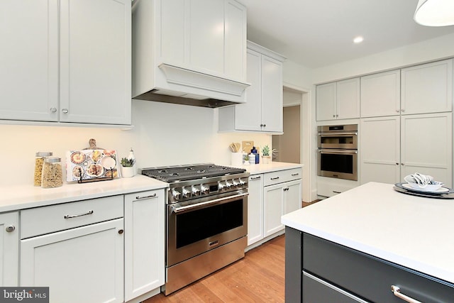 7430 Foundation Way, Springfield, VA 22150 - kitchen with stainless steel appliances, custom range hood, light countertops, light wood-type flooring, and recessed lighting