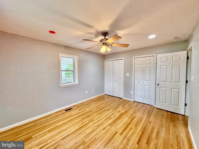 unfurnished bedroom with multiple closets, baseboards, light wood-type flooring, recessed lighting, and ceiling fan