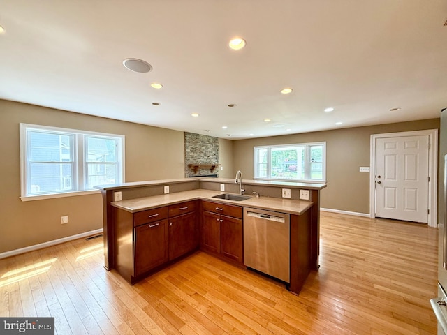 kitchen featuring stainless steel dishwasher, a sink, light countertops, light wood-type flooring, and recessed lighting