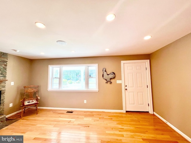 foyer entrance with a fireplace, light wood finished floors, recessed lighting, and baseboards
