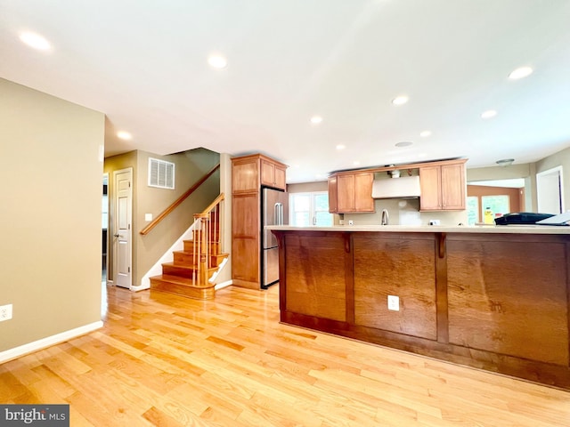 kitchen featuring stainless steel refrigerator, light countertops, light wood-type flooring, baseboards, and recessed lighting