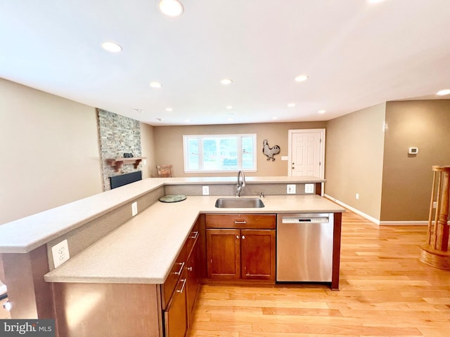 kitchen featuring a sink, stainless steel dishwasher, light wood-type flooring, recessed lighting, and a fireplace