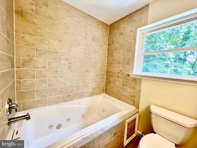 bathroom with toilet and a tub with jets