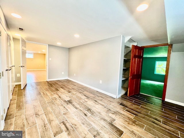 empty room featuring wood tiled floors, baseboards, stairway, and recessed lighting