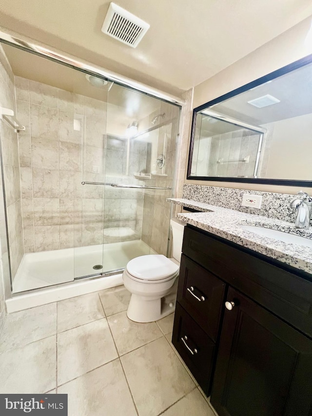 bathroom featuring tile patterned flooring, a stall shower, toilet, and vanity