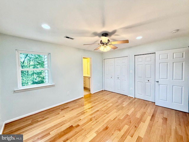 unfurnished bedroom with light wood finished floors, two closets, baseboards, and recessed lighting