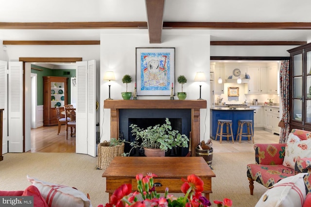 living area with beamed ceiling, light colored carpet, and a fireplace