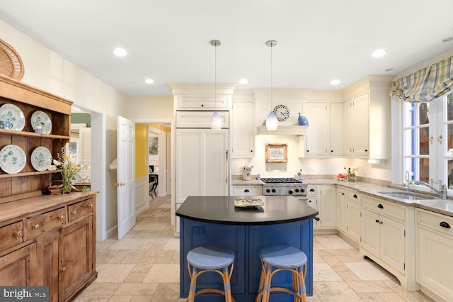 kitchen with a sink, stone tile flooring, a center island, decorative light fixtures, and recessed lighting