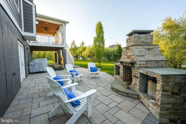 view of patio featuring an outdoor stone fireplace, stairs, and a grill