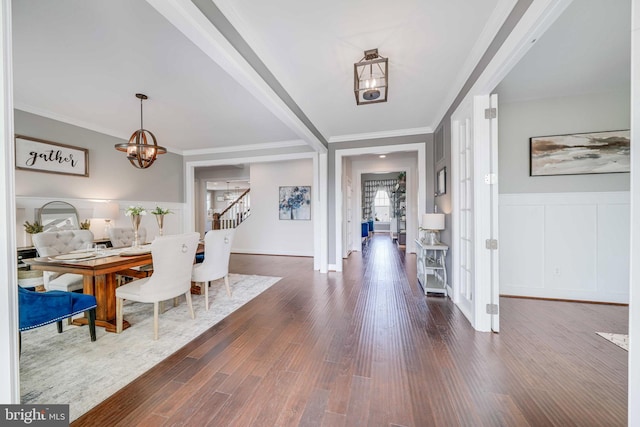 entrance foyer with a chandelier, dark wood-type flooring, stairway, crown molding, and a decorative wall