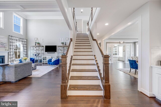 stairway featuring wood-type flooring, recessed lighting, a glass covered fireplace, and ornamental molding