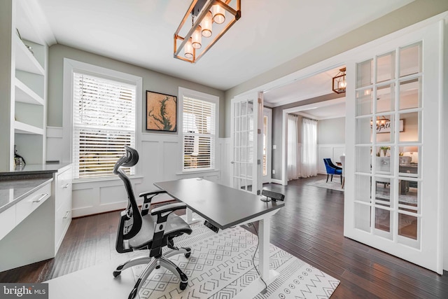 home office with a decorative wall, a wainscoted wall, dark wood-style flooring, healthy amount of natural light, and a chandelier
