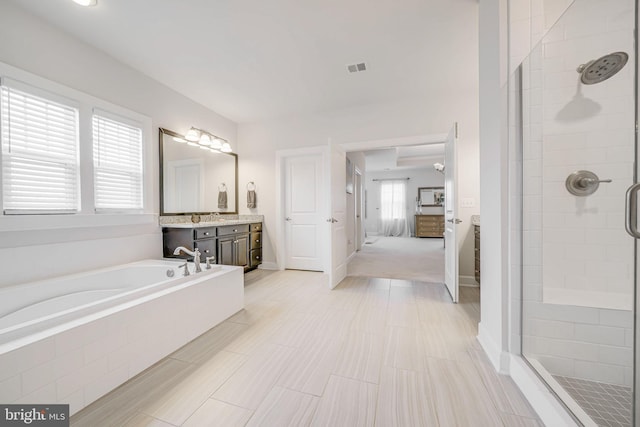 full bathroom with connected bathroom, a stall shower, a garden tub, vanity, and baseboards