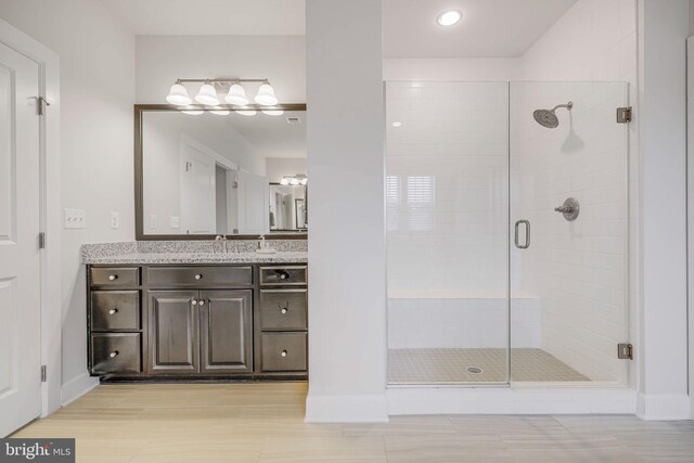 bathroom featuring a shower stall, vanity, baseboards, wood finished floors, and recessed lighting