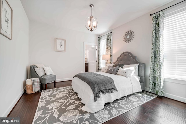 bedroom with baseboards, a chandelier, and wood finished floors