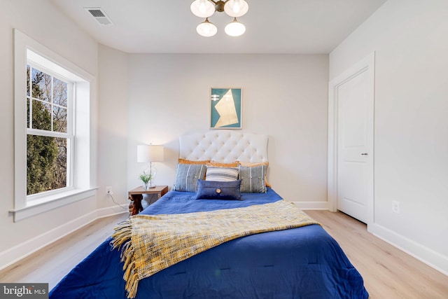 bedroom with wood finished floors, baseboards, and a chandelier
