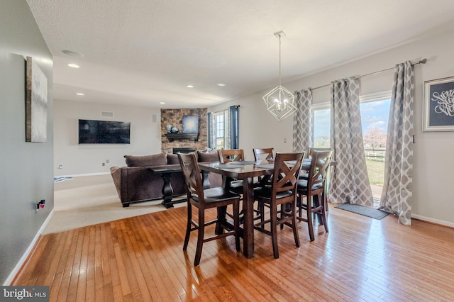 269 Bucktail Dr, Middletown, DE 19709 - dining space featuring light wood-type flooring, baseboards, a chandelier, a stone fireplace, and recessed lighting