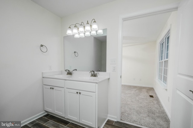 bathroom with baseboards, double vanity, and wood finished floors