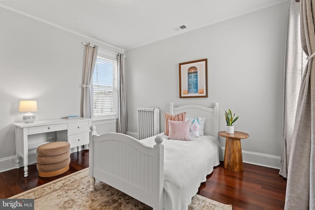 bedroom with radiator heating unit, wood finished floors, and baseboards
