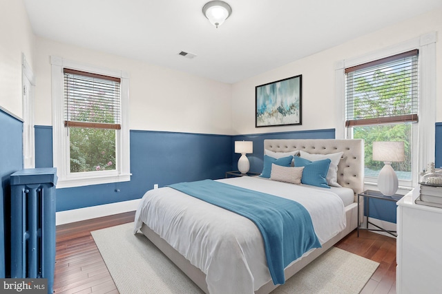 bedroom with wood finished floors, radiator heating unit, and baseboards