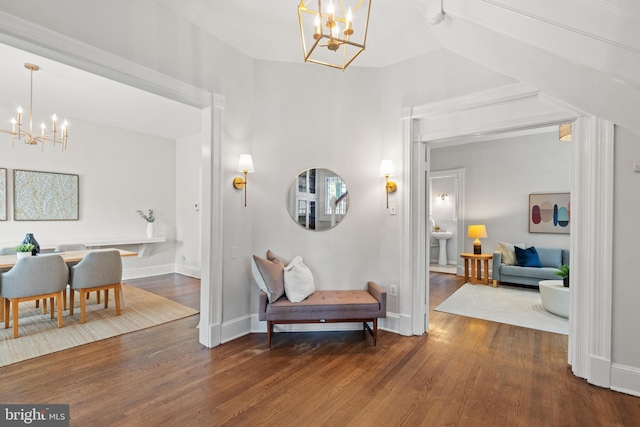 hall with a chandelier, wood finished floors, baseboards, and lofted ceiling