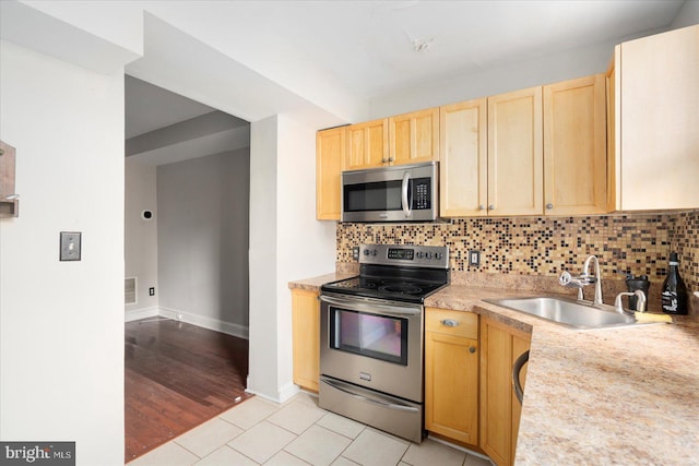 15 N Belnord Ave, Baltimore, MD 21224 - kitchen featuring stainless steel appliances, light brown cabinets, light countertops, and decorative backsplash