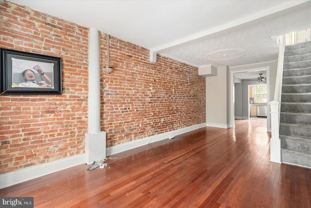 15 N Belnord Ave, Baltimore, MD 21224 - unfurnished living room featuring stairway, hardwood / wood-style flooring, brick wall, and beamed ceiling