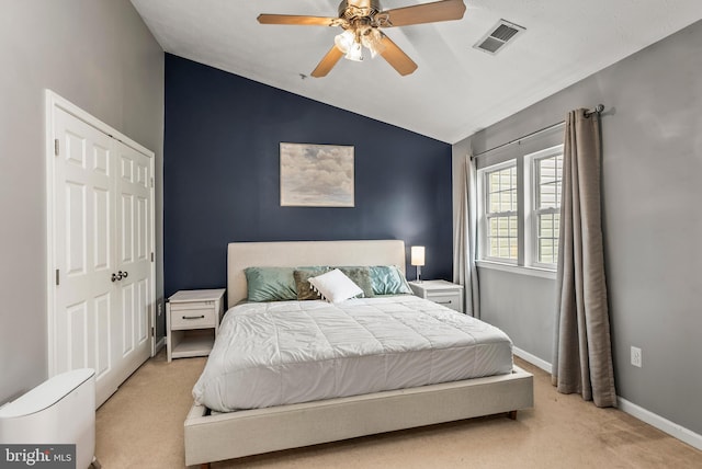 bedroom featuring lofted ceiling, light carpet, a closet, baseboards, and ceiling fan