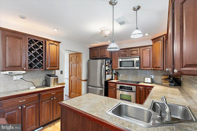 2919 Lexington Ct, Woodbridge, VA 22192 - kitchen featuring appliances with stainless steel finishes, a sink, backsplash, pendant lighting, and a peninsula