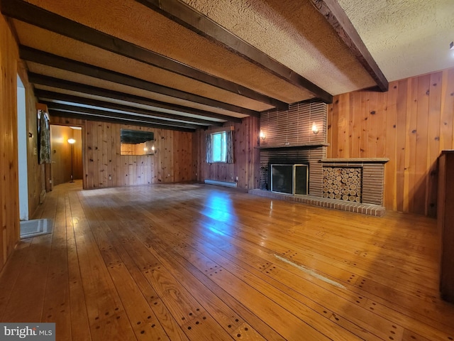 13337 Rowe Rd, Smithsburg, MD 21783 - unfurnished living room featuring a fireplace, beamed ceiling, baseboard heating, wooden walls, and hardwood / wood-style floors
